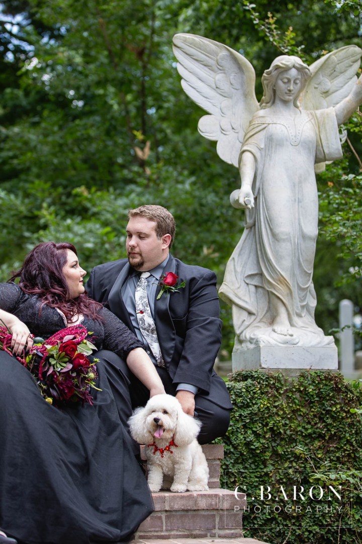 Anniversary session; Black gown; Black tulle dress; C. Baron Photography; Fur Baby; Houston Photographer; Red bouquet; anniversary shoot; black lace cake; cemetary; cemetery; cockapoo; crypt; dark; drippy bouquet; gothic; ravens; red jewelry; red roses; skeleton tie; tombstones; vampy; white poodle;